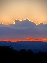 Scenic view of silhouette mountains against romantic sky at sunset