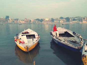 Boats moored in sea by city against sky