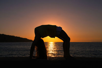 Silhouette man at beach against sky during sunset