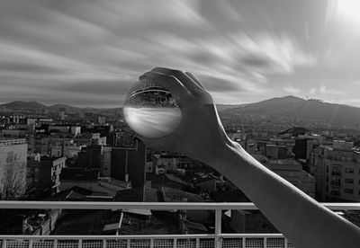 Close-up of hand by railing against buildings in city