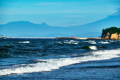 Scenic view of sea with splashing waves against sky