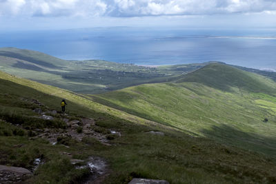 Hiker standing on mountain against sky