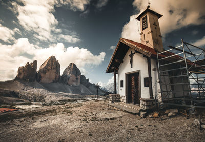 Old building by mountain against sky