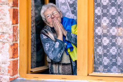 Low angle view of woman looking through window