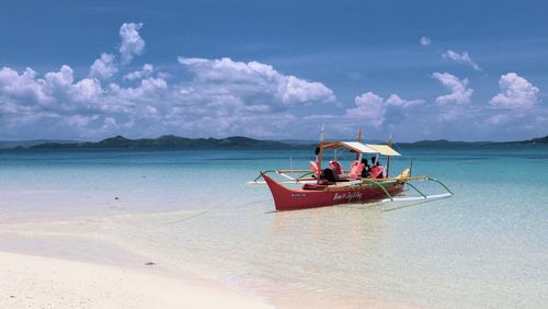 People in boat at sea against cloudy sky