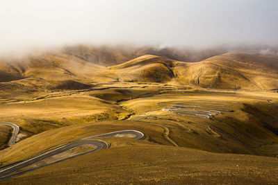 Scenic view of road by mountains against sky