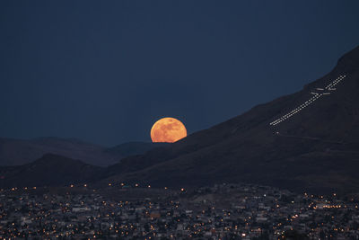 Aerial view of moon over cityscape against clear sky at night