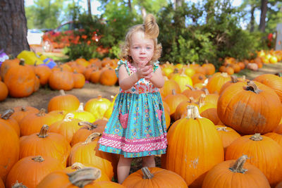 Portrait of girl standing amidst pumpkins at park during autumn
