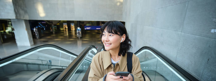 Portrait of young woman sitting on escalator