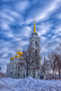 Church by building against sky during winter