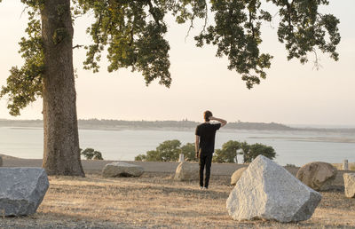 Rear view of young woman on beach against sky