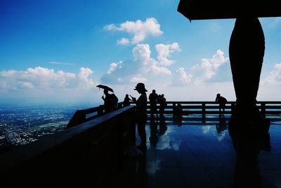 Silhouette people standing by railing against sky