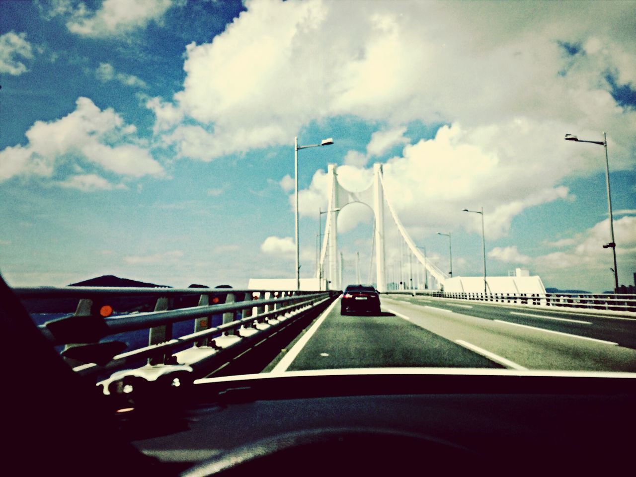 transportation, mode of transport, car, sky, land vehicle, road, cloud - sky, the way forward, road marking, cloudy, cloud, diminishing perspective, street, vehicle interior, on the move, travel, street light, airplane, windshield, vanishing point