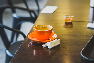 Close-up of orange coffee cup on table