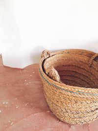 Close-up of wicker basket on table against wall