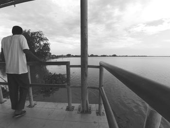 Rear view of man looking at sea against sky