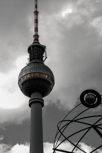 Low angle view of communications tower against cloudy sky