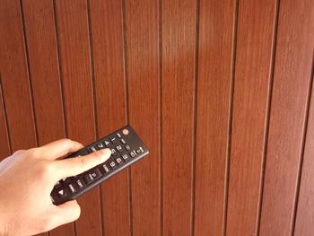 High angle view of hand holding camera on wood