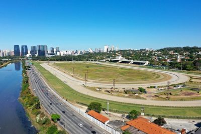 High angle view of road by buildings against clear blue sky