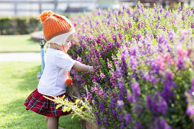 Full length of woman with purple flowers on field