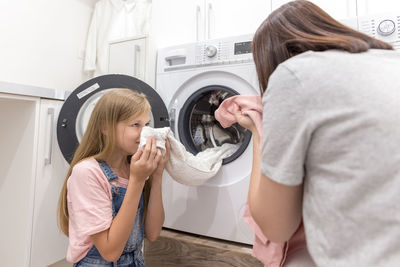 Mother and daughter smelling washed clothes at home
