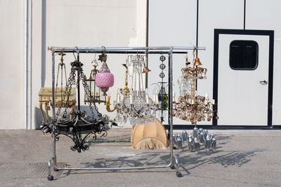 Antique vintage iron and glass chandeliers hanging from a bracket for clothes outdoors.