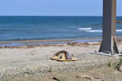 Deck chairs on sand at beach against clear sky