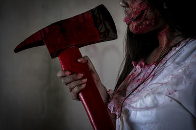 Close-up of young woman with halloween make-up holding axe