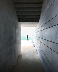 Rear view of man standing by sea seen through tunnel