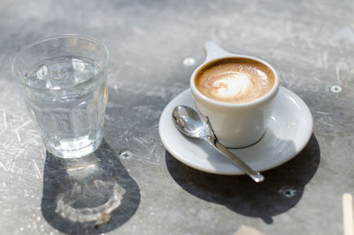 High angle view of cappuccino and drinking glass on table