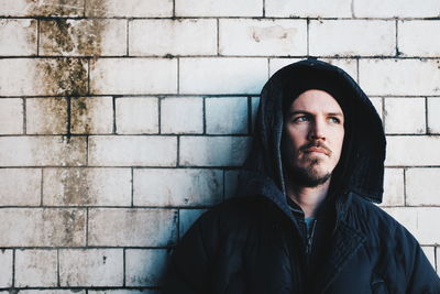 Portrait of young woman standing against wall