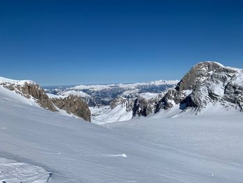 Scenic view of snow covered mountains against clear blue sky