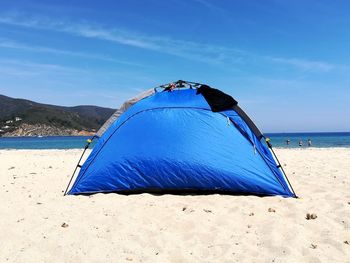 Tent on beach against blue sky