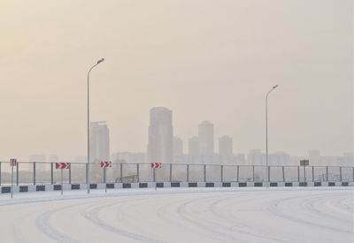 Road by snow covered city against sky