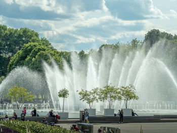 People at fountain against sky