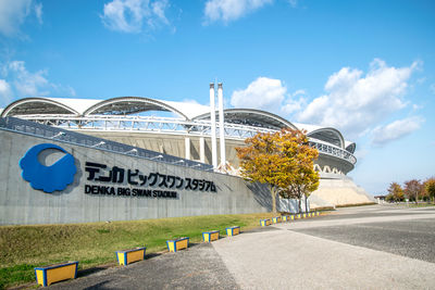 Road by plants in city against sky