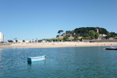 Scenic view of a ribeira beach, baiona, galicia, spain, with boats  on a sunny day and blue sky