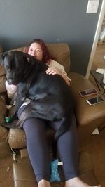 Woman with dog sitting on sofa at home