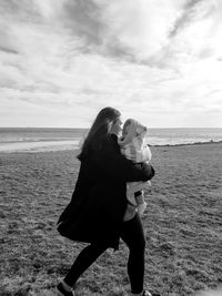 Side view of woman standing on beach holding child 