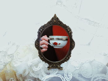 Reflection of woman holding cup in mirror