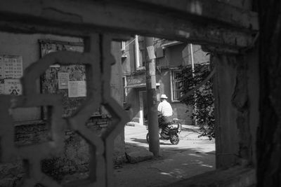 Viewpoint of man riding motorcycle from old walls of townhouse