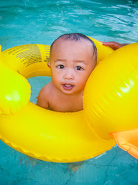 High angle view portrait of toddler with inflatable ring in swimming pool