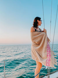 Woman standing by sea against clear sky