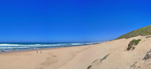 Scenic view of beach against clear blue sky