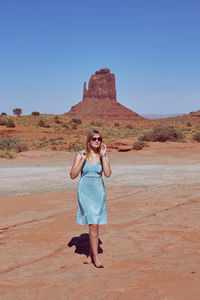 Full length of woman standing on land against clear blue sky