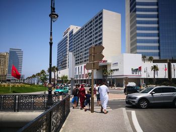 People walking on road by buildings in city