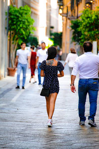 Rear view of people walking on walkway in city