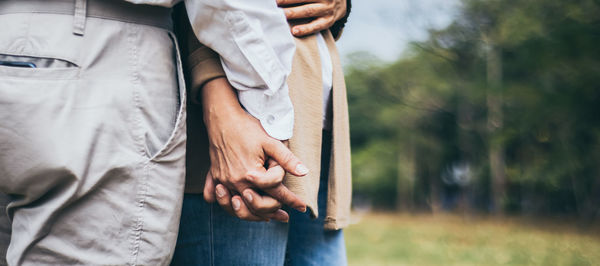 Midsection of couple holding hands