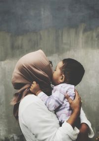 Mother with son standing against wall