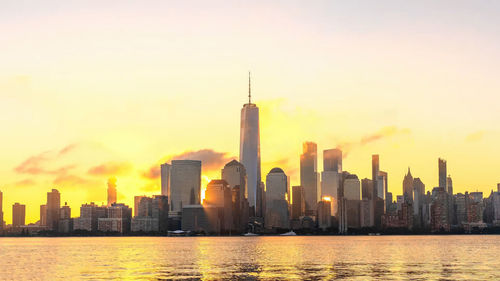 Modern buildings in city against sky during sunset